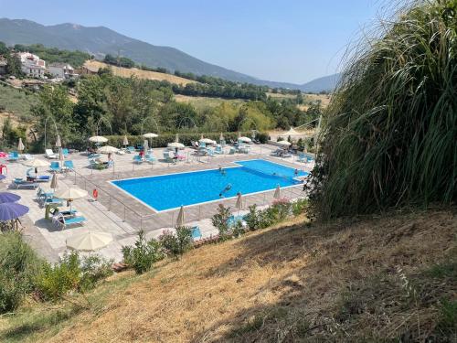 a large swimming pool with chairs and umbrellas on a hill at Il Pozzo Country House in Collescipoli