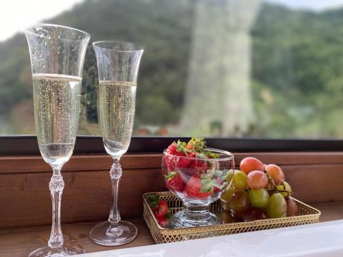 two champagne glasses and a bowl of fruit on a table at Cabana Amor Perfeito in Alfredo Wagner