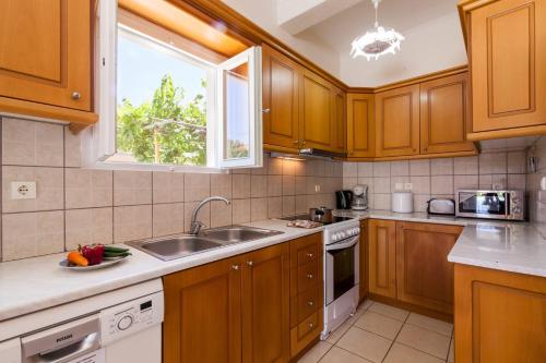 a kitchen with wooden cabinets and a sink and a window at Villa Stafili by Villa Plus in Litherés