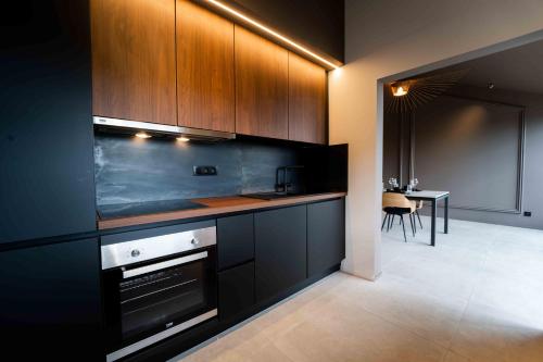 a kitchen with black cabinets and a dining room with a table at Luxury Penthouse & Terrace - Mons City Center in Mons