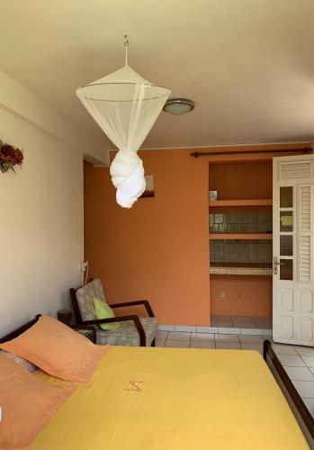a bedroom with a yellow bed and a chandelier at Studio Griyav- dans villa les Polycias in Sainte-Luce