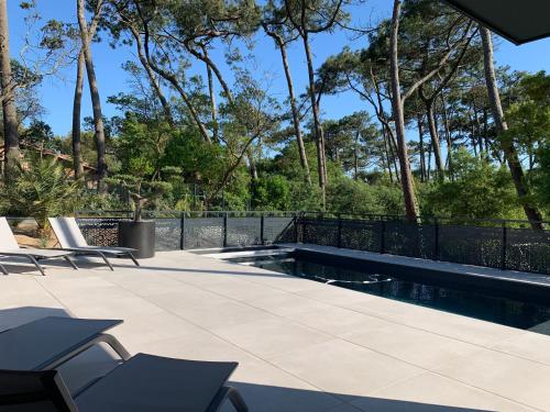un patio con piscina, sillas y árboles en Villa Aréna à Labenne-Océan, en Labenne