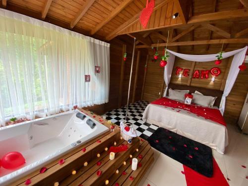 a bedroom with a bed and a bath tub at Cabana Dois Amores. Destino romântico. in Barracão