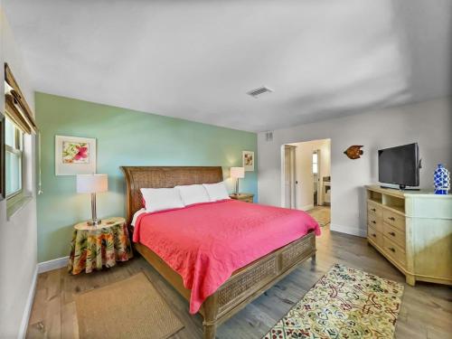 a bedroom with a red bed and a television at Spacious Updated Condo Just 2 Blocks to Siesta Key Beach in Siesta Key