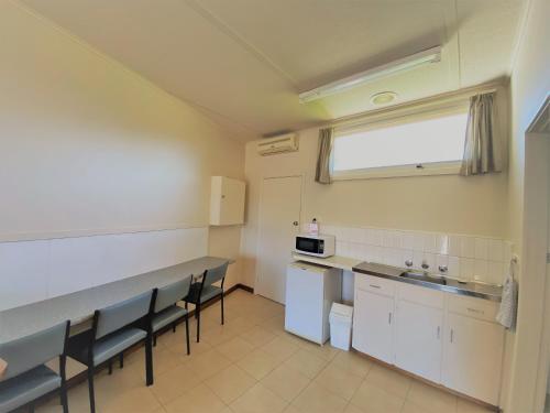 - une cuisine avec des tables et des chaises dans une pièce dans l'établissement The Terang Motor Inn, à Terang