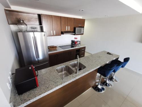 a kitchen with a stainless steel refrigerator and blue stools at APARTAMENTO CON ALBERCA en Mazatlán in Mazatlán