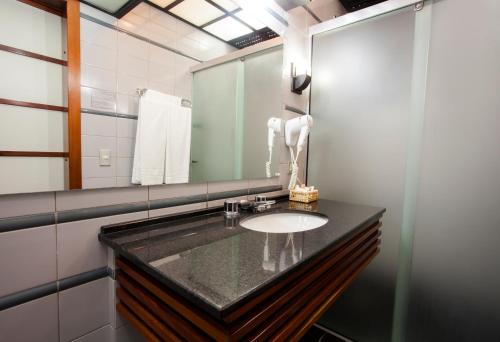 a bathroom with a sink and a mirror at Hotel Nikko in Curitiba