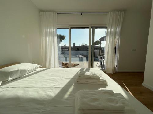 Un dormitorio con una cama blanca con toallas. en Samoqueira 12, en Porto Covo
