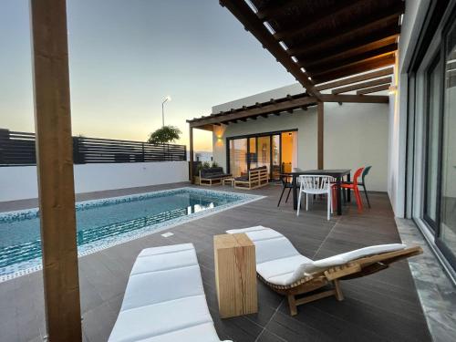 a patio with a table and chairs and a swimming pool at Samoqueira 12 in Porto Covo
