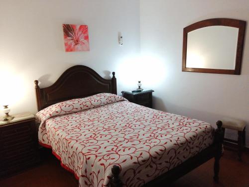a bedroom with a bed with a red comforter and a mirror at Hostel Boutique Marisol in Monte Gordo