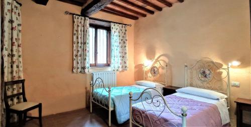 a bedroom with two beds and a window at CAMPO AL VENTO - Country farm in Monte Castello di Vibio