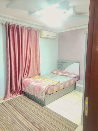 a small bedroom with a bed and a pink curtain at Four Seasons in Cairo