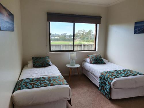 a small room with two beds and a window at Shepparton Golf Motel in Shepparton