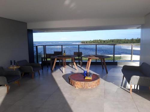 a room with tables and chairs and a view of the ocean at FLAT BEIRA MAR BARRA DE JANGADA ANDAR ALTO JABOATão in Recife