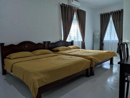 um quarto com 2 camas com lençóis amarelos e janelas em Kayangan Inn em Rantau Panjang