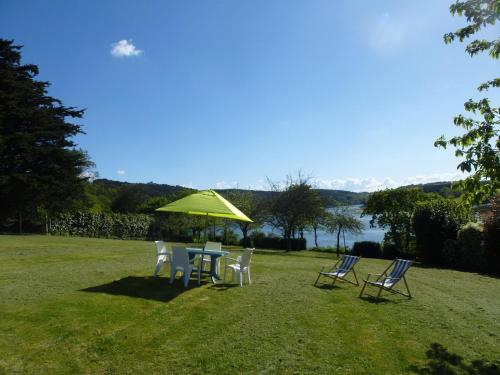 a table and chairs with a green umbrella at Holiday Home near Goëlo Coast & Beaches in Plourivo