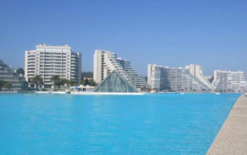 a large pool of blue water in front of buildings at San Alfonso 507 in Algarrobo