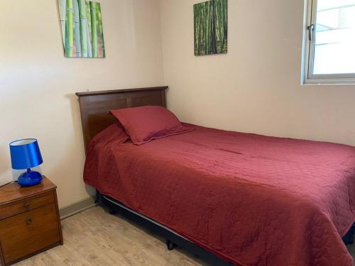 a small bedroom with a red bed and a night stand at San Alfonso 507 in Algarrobo