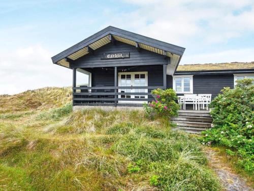 a black house on top of a grassy hill at 6 person holiday home in Ringk bing in Søndervig