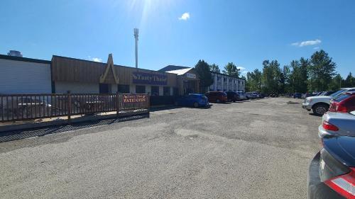 a parking lot with cars parked in front of a building at Sundre Motor Inn in Sundre