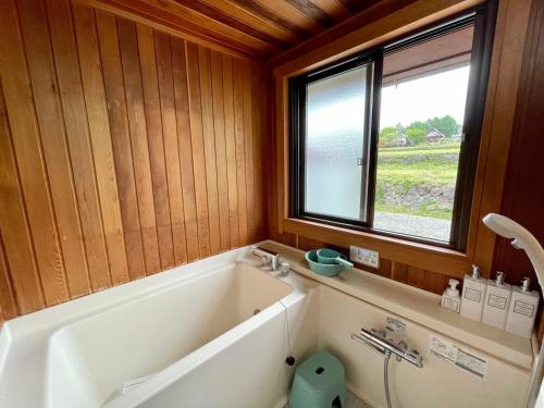 a bathroom with a bath tub and a window at 八ヶ岳 HOKUTO BASE -Yatsugatake- in Hokuto