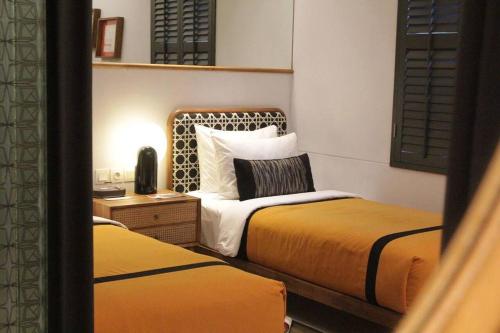 a hotel room with two beds and a desk with a bedsenalsenal at Kosenda Hotel in Jakarta