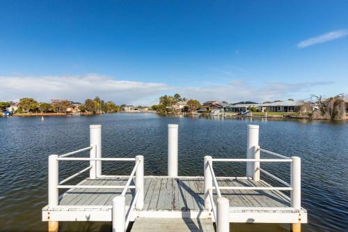deux chaises assises sur un quai sur un lac dans l'établissement Waterfront on Forster Keys, à Forster