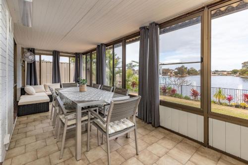 a dining room with a table and chairs and windows at Waterfront on Forster Keys in Forster