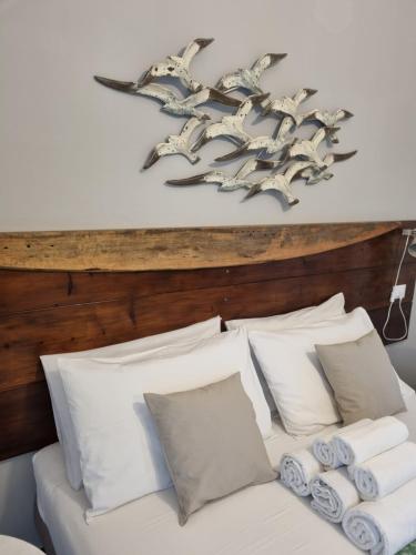 a bed with white pillows and birds on the wall at VILLA VILLACOLLE in Procchio