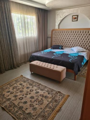 ein Schlafzimmer mit einem Bett, einer Ottomane und einem Teppich in der Unterkunft Villa le bonheur 