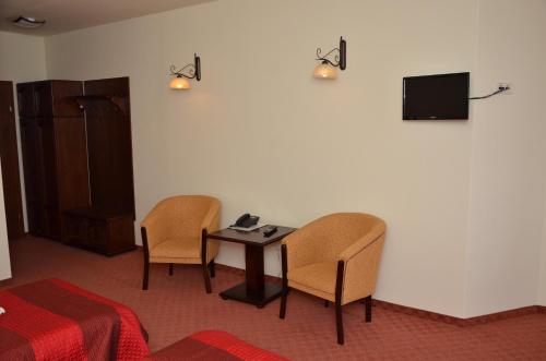 a room with a table and two chairs and a television at Hotel Restaurant La Conac in Botiz
