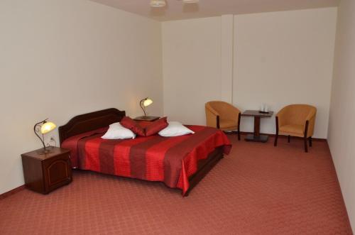 a bedroom with a bed and a table and chairs at Hotel Restaurant La Conac in Botiz