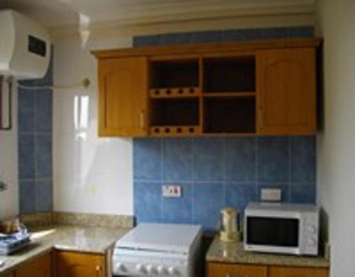 cocina con armarios de madera y microondas blanco en Calabash Green Executive Apartments, en Accra