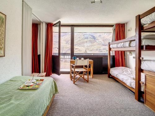 - une chambre avec des lits superposés et un bureau avec une table dans l'établissement Appartement Skis aux Pieds - Balcon Sud, 6 Pers., 1 Chambre, Wifi - FR-1-344-1049, aux Menuires