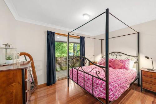 ein Schlafzimmer mit einem Bett mit Baldachin und rosa Bettwäsche in der Unterkunft Seaholme at Cowan Cowan in Cowan Cowan