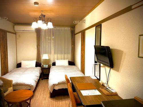 a room with two beds and a table and a tv at Daigo House in Daigo