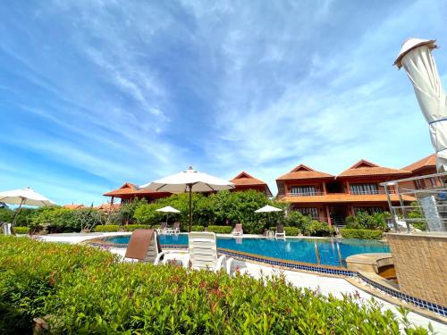 a resort swimming pool with umbrellas and a resort at PS Thana Resort in Choeng Mon Beach