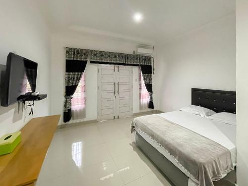 sypialnia z łóżkiem i telewizorem w obiekcie Hotel Lucky 21 Syariah Mitra RedDoorz w mieście Tabahpingin