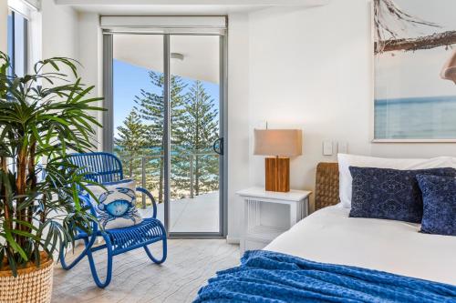 Un dormitorio con una cama y una silla azul. en The Garland at Rainbow Bay, en Gold Coast