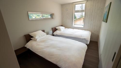 two beds in a small room with two windows at Hakuba View Villa in Hakuba