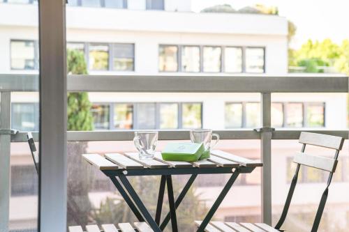 a table with two glasses and a plate on a balcony at Prado I - Coeur Perrier balcon proche Velodrome in Marseille