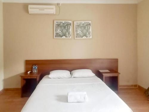 een slaapkamer met een wit bed en 2 tafels bij Hotel Shafira Pariaman Syariah Mitra RedDoorz in Pariaman