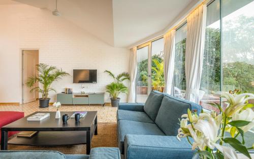 a living room with a blue couch and a table at El Sereno 2 BHK Stylish Apartments In Vagator with Garden and Pool- 10 minutes drive to Vagator Beach in Chapora