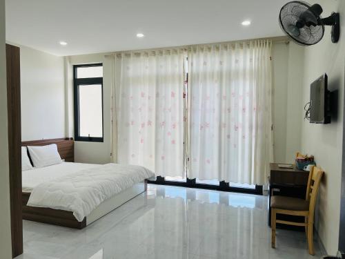 1 dormitorio con cama, escritorio y ventana en Cô Ba Homestay en Quy Nhon
