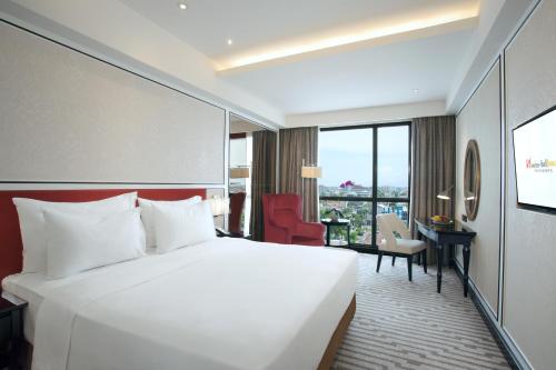 a hotel room with a large bed and a desk at Swiss-Belboutique Yogyakarta in Yogyakarta
