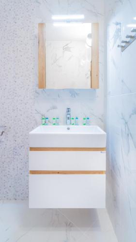 a white bathroom with a sink and a mirror at Guest House Karamihalevi in Sozopol