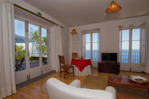 a living room with a table and a television at Casa do Lado in Povoação