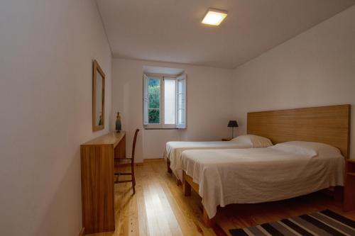 a bedroom with two beds and a desk and a window at Casa do Lado in Povoação