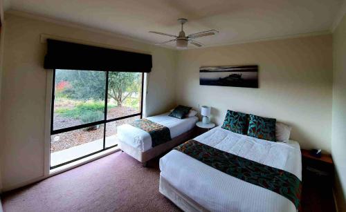 a bedroom with two beds and a large window at Shepparton Golf Motel in Shepparton
