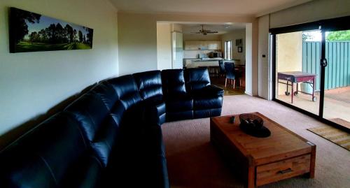 a living room with a black leather couch and a coffee table at Shepparton Golf Motel in Shepparton